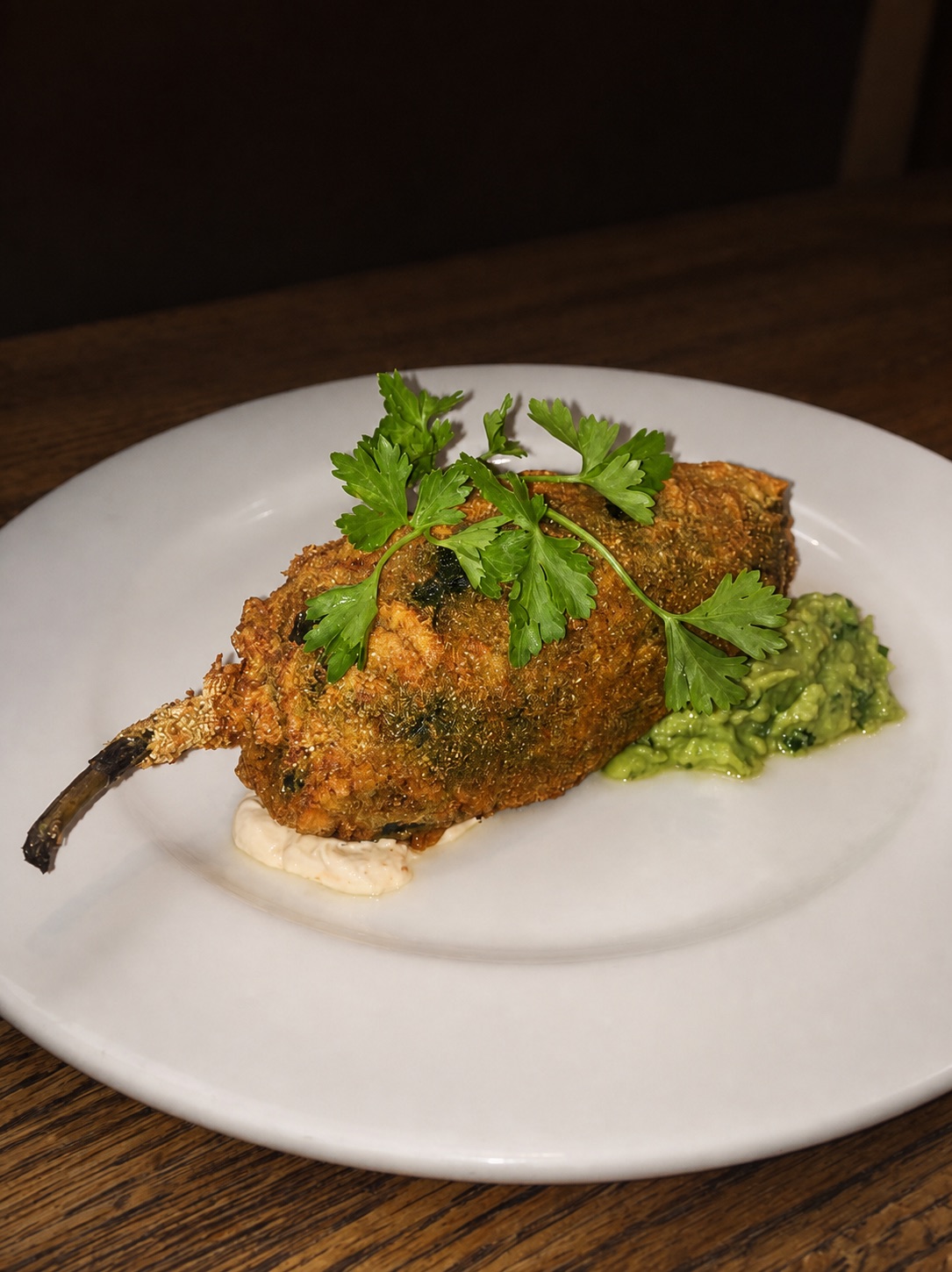 Crisp chile relleno plated with guacamole and house sauce
